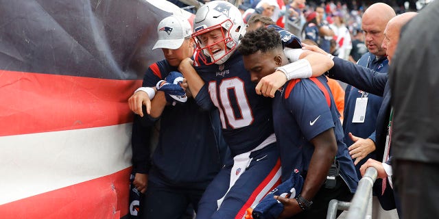 New England Patriots quarterback Mac Jones is helped off the field after suffering a leg injury with less than two minutes to play in the second half of a game against the Baltimore Ravens, Sunday, Sept. 25, 2022, in Foxborough, Mass.