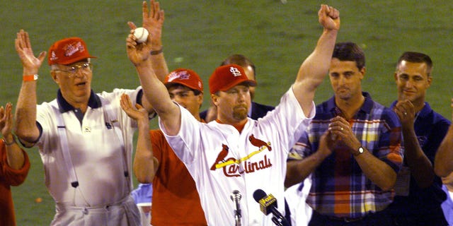 Mark McGwire(C) of the St. Louis Cardinals holds the ball he hit for his 62nd home run of the season against the Chicago Cubs, given to him by Tim Forneris(2ndL), as father John McGwire (L), Roger Maris Jr.(2ndR) and Kevin Maris look on Sept. 08 at Busch Stadium in St. Louis, MO.  McGwire broke the home run record of 61 for the season set by Roger Maris in 1961.
