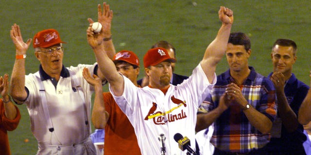 St. Louis Cardinals' Mark Maguire (C) holds the ball that hit his 62nd home run of the season against the Chicago Cubs given by Tim Fornellis (2ndL) as father John Maguire (L), Roger. Maris Jr. (2ndR) and Kevin Maris watch at Bush his stadium in St. Louis, Missouri, Sept. 8. Maguire broke the 61-season home run record set by Roger Maris in 1961.