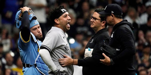 New York Yankees' Marwin Gonzalez, middle, reacts as he's checked on by a trainer after being hit by an errant throw from Milwaukee Brewers' Victor Caratini during the third inning of a baseball game Saturday, Sept. 17, 2022, in Milwaukee. Gonzalez exited the game.