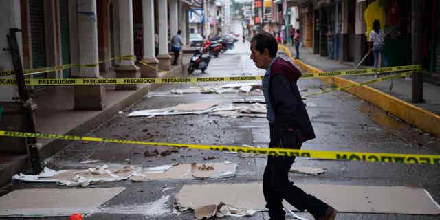 A man walks down a street in Coalcoman, Mexico on September 20, 2022, after being damaged in an earthquake the day before.