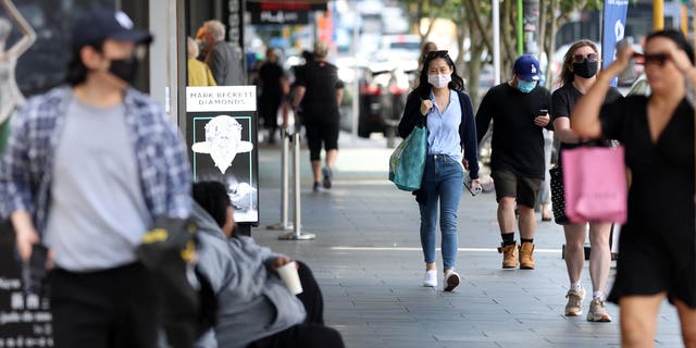 New Zealand has removed many of its COVID restrictions such as mask and vaccine mandates as worries around the pandemic begin to cool. Pictured: People walk down a street in Auckland, New Zealand, on Nov. 10, 2021.