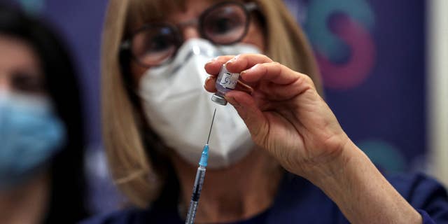 A nurse prepares to administer a COVID vaccine.