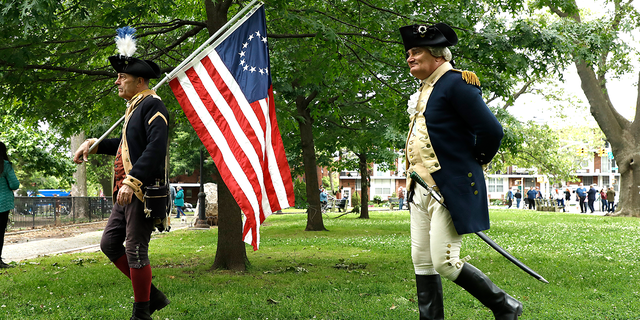 Revolutionary war reenactors walk with a US flag in celebration of Memorial Day in John Paul Jones Park in Bay Ridge on May 31, 2021, in the Brooklyn borough of New York City.