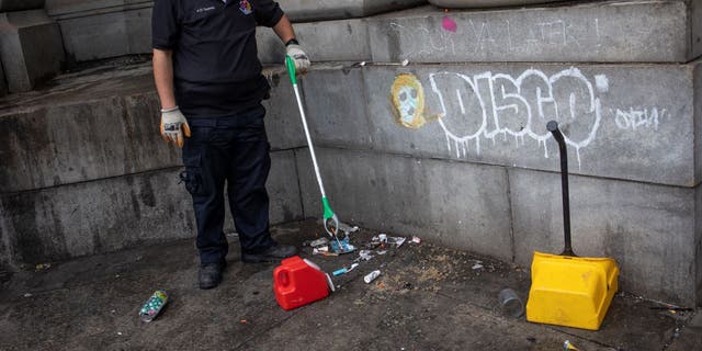 A member of a the Department of Sanitation Environmental Police collects used needles as part of a city sweep of a homeless encampment, September 22, 2022 in New York City, New York. 