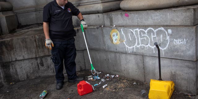A member of a the Department of Sanitation Environmental Police collects used needles as part of a city sweep of a homeless encampment, September 22, 2022 in New York City, New York.