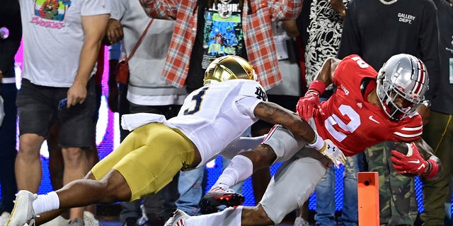 Ohio State wide receiver Emeka Egbuka, right, scores a touchdown as he is hit by Notre Dame safety Houston Griffith, left, during the first quarter of an NCAA college football game on Saturday, September 3, 2022 in Columbus, Ohio.