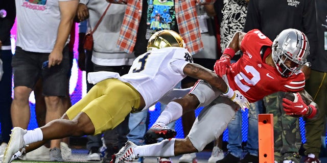 Ohio State wide receiver Emeka Egbuka, right, scores a touchdown as he is hit by Notre Dame safety Houston Griffith, left, during the first quarter of an NCAA college football game on Saturday, September 3, 2022 in Columbus, Ohio.