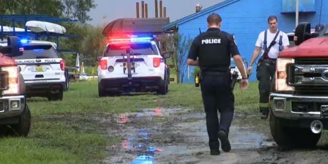 Orlando police officers walk toward firefighters searching for missing oarsmen after lightning strikes on Lake Fairview.