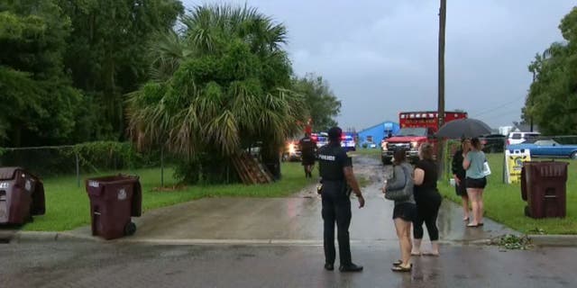 Un oficial de policía de Orlando habla con mujeres cerca del lago Fairview mientras los equipos buscan a un remero desaparecido luego de un rayo el 15 de septiembre de 2022.