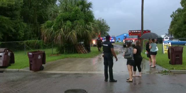 An Orlando police officer talks to women near Lake Fairview as crews search for a missing rower following a lightning strike on Sept. 15, 2022.