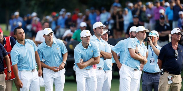 Xander Schauffele, Jordan Spieth, Sam Burns, Scottie Scheffler, Assistant Captain Fred Couples, Cameron Young and Justin Thomas of Team USA look on as Max Homa and Tony Finau of Team USA play the 18th green during Thursday's foursomes of the day .  one of the 2022 Presidents Cup at Quail Hollow Country Club on September 22, 2022 in Charlotte, North Carolina.