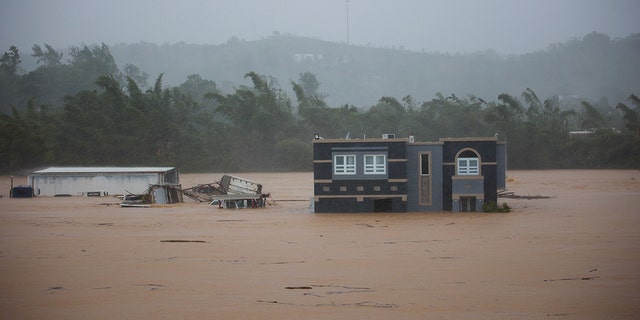 A home is submerged in floodwaters caused by Hurricane Fiona in Cayey, Puerto Rico, Sunday, Sept. 18, 2022.  According to authorities three people were inside the home and were reported to have been rescued. 