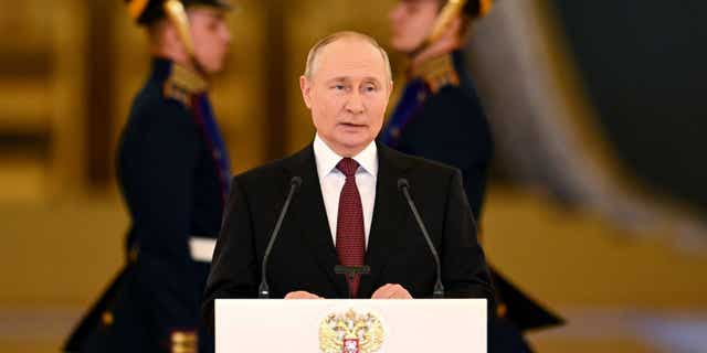 Vladimir Putin gives a speech surrounded by men in military uniforms.  (AP)