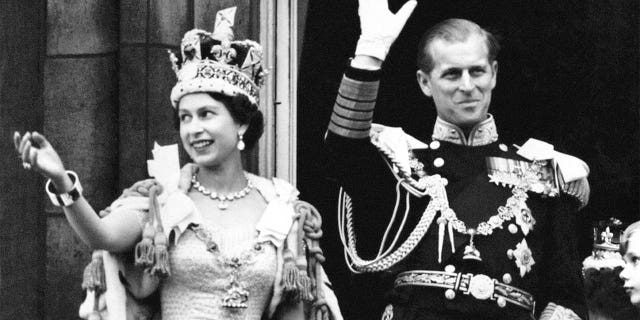 Queen Elizabeth II in the Imperial State Crown and the Duke of Edinburgh in Admiral of the Fleet uniform wave from the balcony to the watching crowd around the gates of Buckingham Palace after the coronation. (Photo by PA Images via Getty Images)