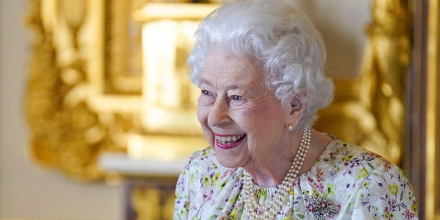Britain's Queen Elizabeth II smiles as she arrives to view a display of artifacts from Halcyon Days to commemorate the company's 70th anniversary in the White Drawing Room at Windsor Castle on March 23, 2022. - The Queen viewed a selection of hand-decorated archive enamelware and fine bone china from Halcyon Days, including their earliest designs from the 1950s.