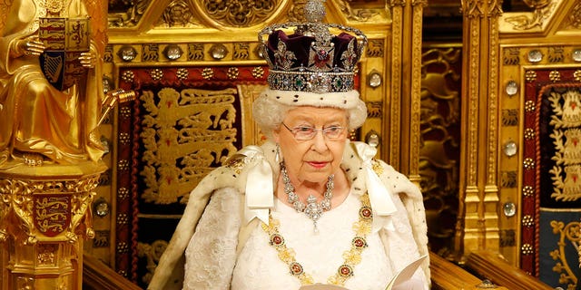 Queen Elizabeth II sits upon a golden throne.