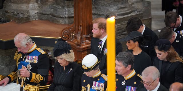 Prince Harry and Meghan Markle sit behind King Charles III and Queen Consort Camilla at the Queen's funeral on Monday, Sept. 19. 