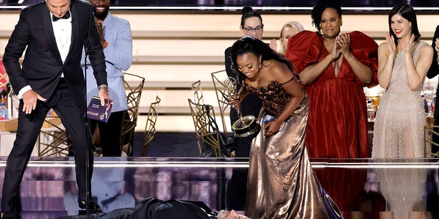 Quinta Brunson (R) accepts Outstanding Writing for a Comedy Series for "Abbott Elementary" from Will Arnett (L) while Jimmy Kimmel lies onstage during the 74th Primetime Emmys at Microsoft Theater on Sept. 12, 2022 in Los Angeles. 