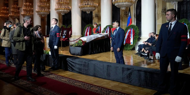 People walk past the coffin of former Soviet President Mikhail Gorbachev inside the Pillar Hall of the House of the Unions during a farewell ceremony in Moscow, Russia, Saturday, Sept. 3, 2022. Gorbachev, who died Tuesday at the age of 91, will be buried at Moscow's Novodevichy cemetery next to his wife, Raisa, following a farewell ceremony at the Pillar Hall of the House of the Unions, an iconic mansion near the Kremlin that has served as the venue for state funerals since Soviet times. (AP Photo/Alexander Zemlianichenko)