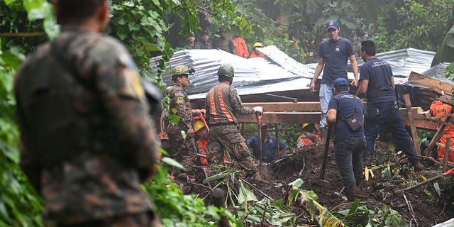 Two children died drowning when they were swept away in a rain-swollen gully in El Salvador. Pictured: Soldiers and rescuers try to recover the bodies of people who died after a landslide caused by heavy rain in Huizucar, El Salvador, on Sept. 22, 2022. 