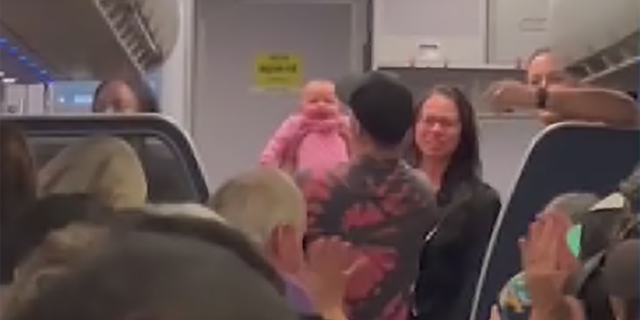 The baby's father holds his daughter who had stopped breathing on a flight to Orlando but was revived by a nurse on board.