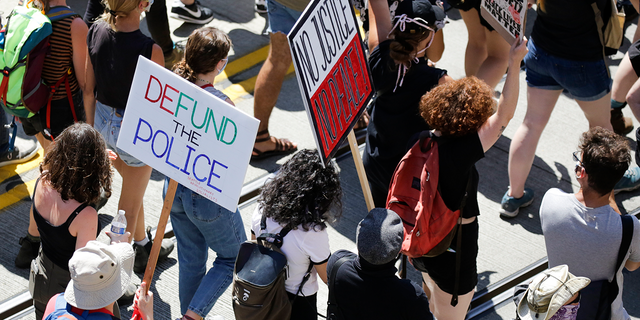 People carry signs during a "Defund the Police" march from King County Youth Jail to City Hall in Seattle, Washington on August 5, 2020. (Photo by Jason Redmond / AFP) (Photo by JASON REDMOND/AFP via Getty Images) 