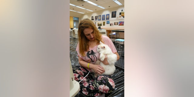 A woman holds her cat at a school that's been turned into a pet-friendly storm shelter in Seminole County, Florida.