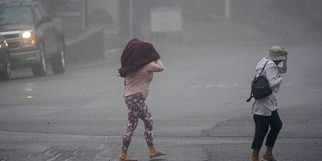 Tropical Storm Kay weakened into a post tropical cyclone on Sept. 9 as it veered away from the Mexico-California border. Pictured: People cross the road as wind and rain pummel Julian, California, on Sept. 9, 2022.