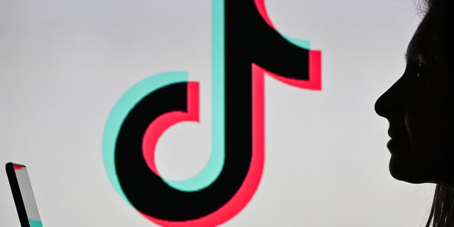 An image of a woman holding a cell phone in front of a TikTok logo displayed on a computer screen in Edmonton, Alberta, Canada, on Jan. 12, 2021.