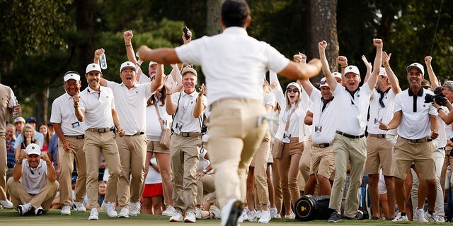 The international team cheers as Tom Kim of South Korea and the international team celebrate his hole-winning putt to win the Match 1 Up with teammate Si Woo Kim of South Korea against Patrick Cantlay and Xander Schauffele on September 24, 2022 in Charlotte, North Carolina.