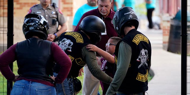 A student hugs an officer in uniform wearing a helmet and protective gear