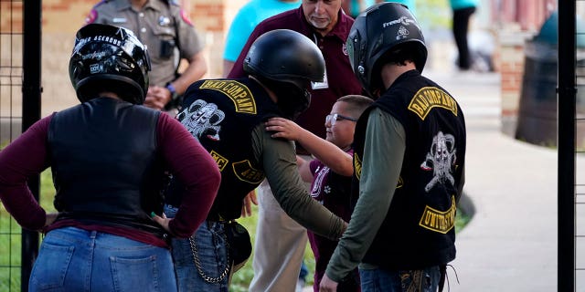 A student hugs an officer in uniform wearing a helmet and protective gear