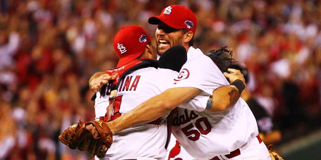 Adam Wainwright (50) and Yadier Molina (4) of the St. Louis Cardinals celebrate after defeating the Pittsburgh Pirates 6-1 in Game 5 of the National League Division Series at Busch Stadium on October 9, 2013 in St. Louis.