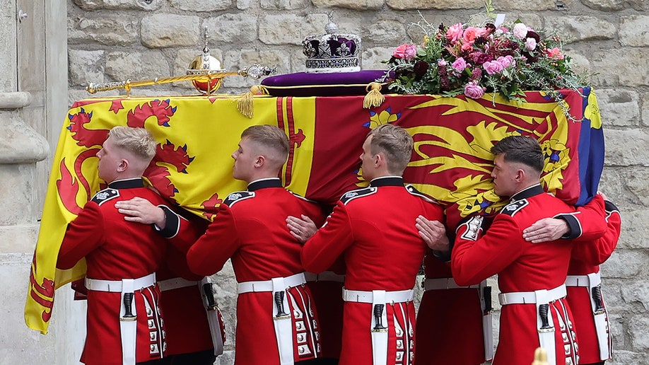 Guards in red uniforms carry Queen Elizabeth's coffin