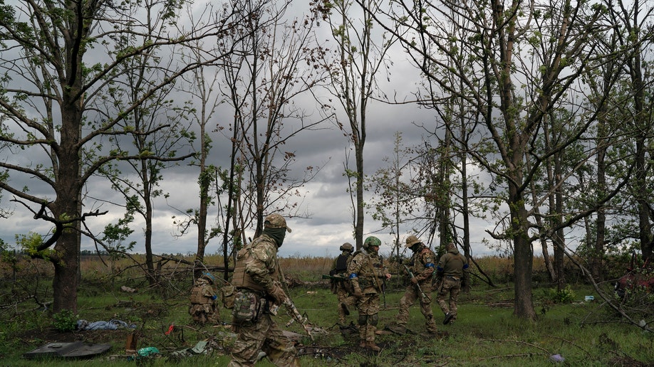 Ukrainian servicemen check the site where a body of a Ukrainian soldier was found inside an armored vehicle