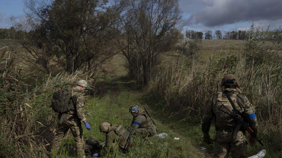 Ukrainian national guard servicemen examine the body