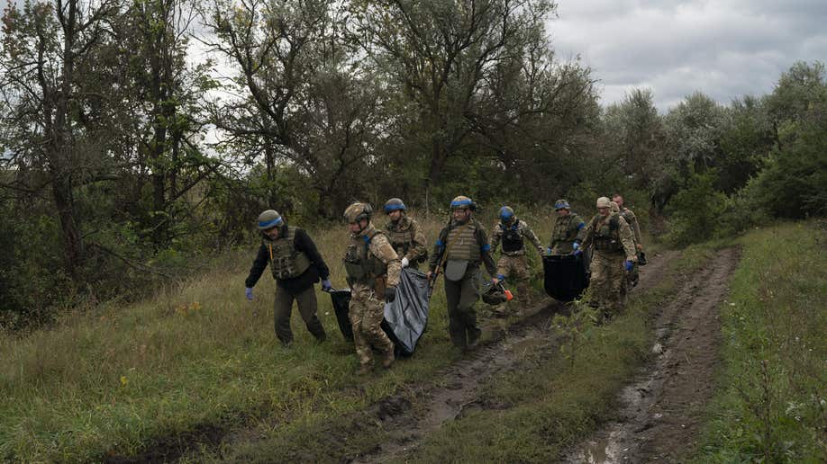 Ukrainian national guard servicemen carry bags containing the bodies of two Ukrainian soldiers