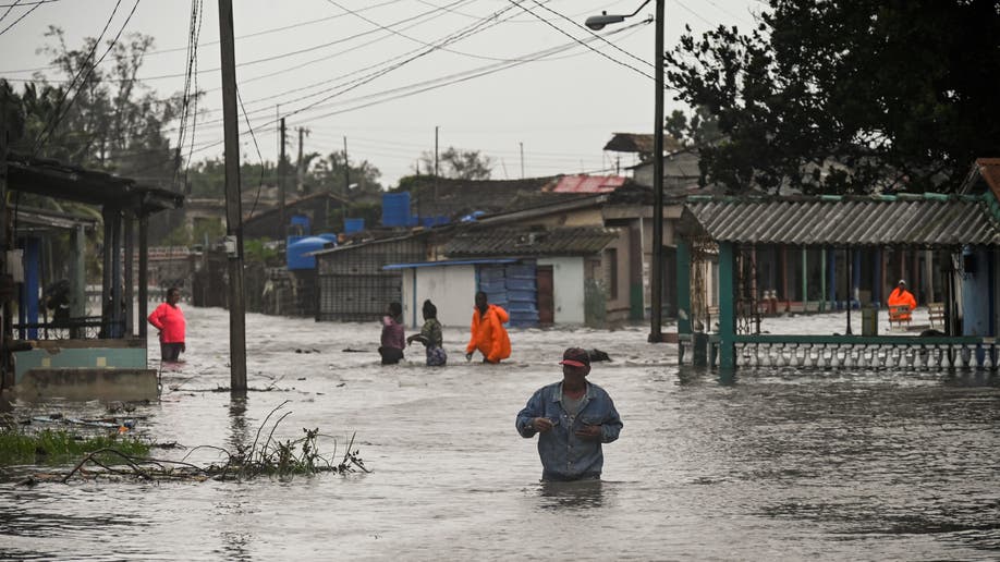 People walk through a flooded street in Batabano, Cuba