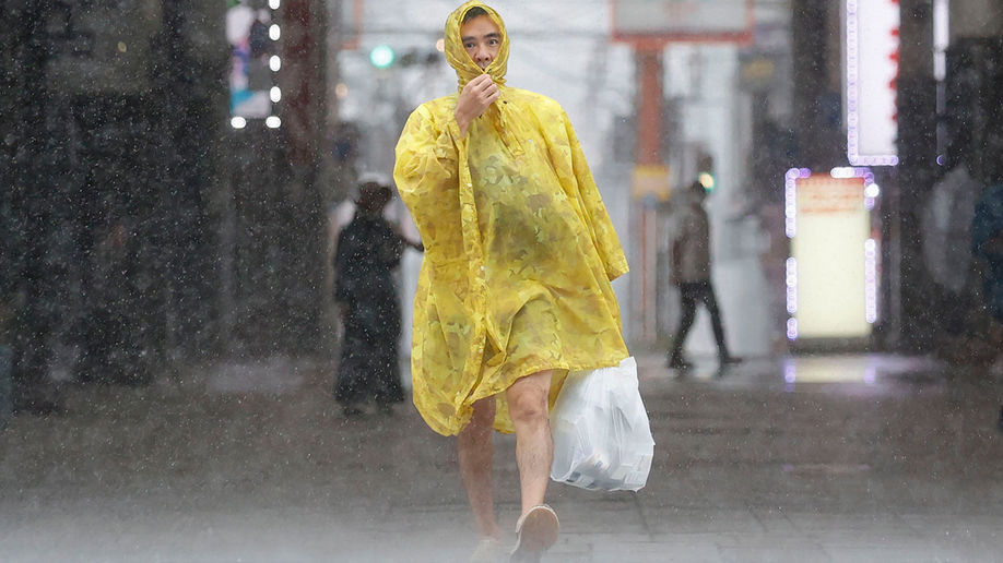 A man makes his way through the heavy rain caused by a powerful typhoon