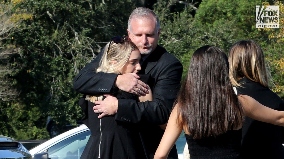 Paul Rice hugs a mourner at his daughter Alllison Rice's funeral