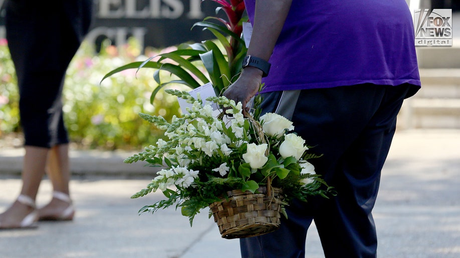 A woman carries flowers into the church for Allison Rice's funeral