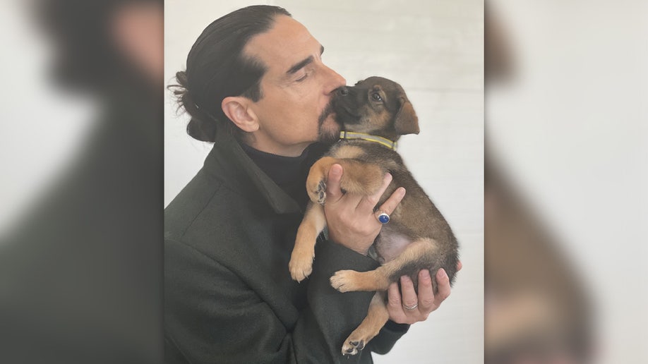 Kevin Richardson holding and kissing a small puppy