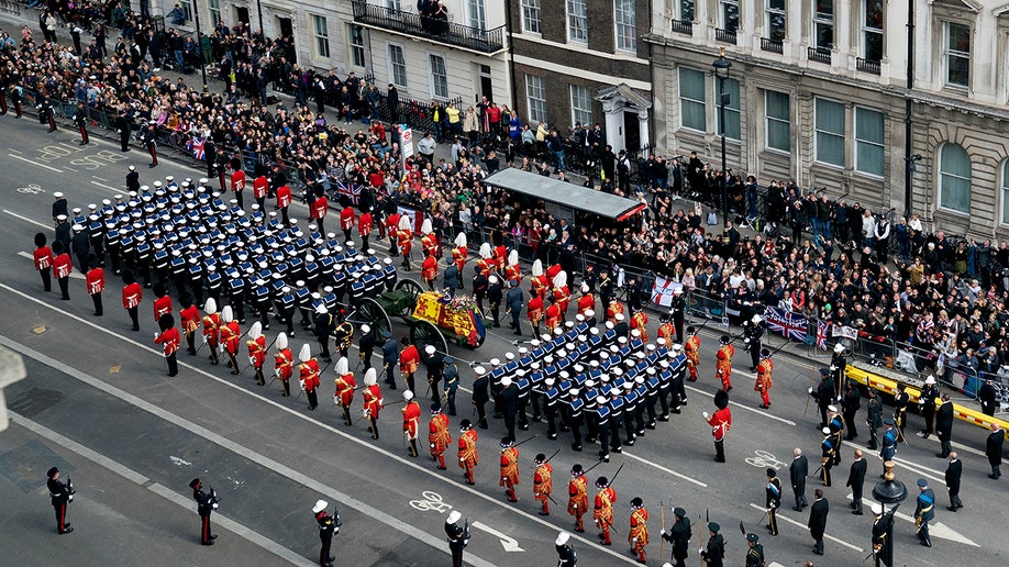 Aerial shot over Queen Elizabeth's funeral processin with guards standing all around her casket.