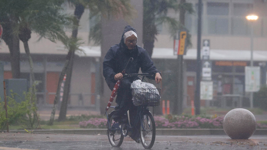 A man on a bicycle makes his way through the rain