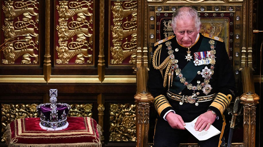 Prince Charles sits on a golden thrown with a crown on a cushion to his right