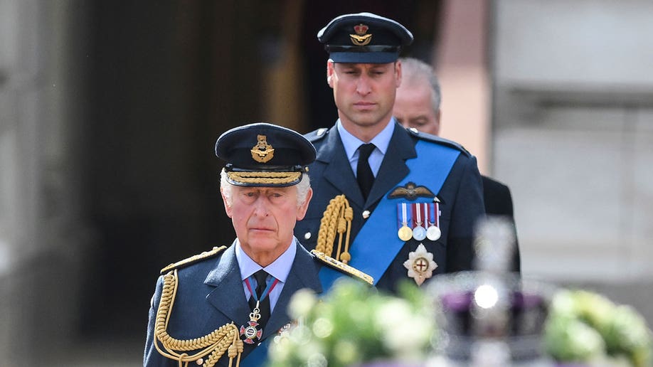 King Charles III and Prince William wearing military uniforms marching behind Queen Elizabeth's coffin