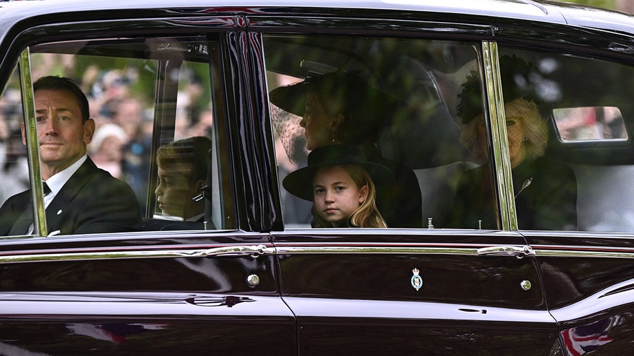 Princess Charlotte pears out her window en route to Westminster Abbey for Queen Elizabeth's state funeral