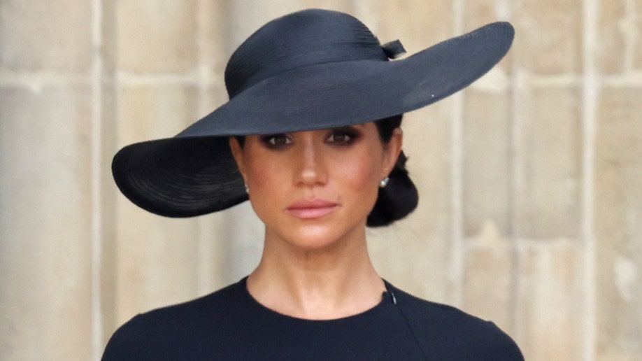 Meghan Markle wears a sad expression while standing outside of Westminster Abbey during Queen Elizabeth's state funeral.
