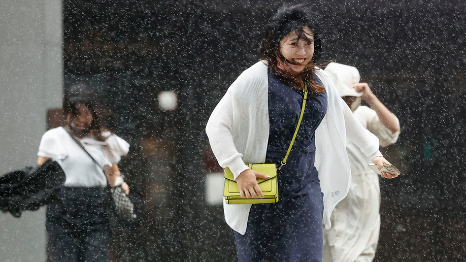 People make their way through the strong wind and rain